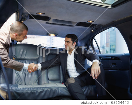 Businessmen Meeting In Limousine And Shaking Hands Businessmen Meeting In Limousine And Shaking Hands 68554443