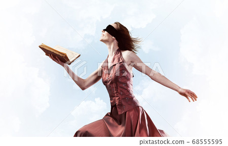 Girl against cloudy sky with opened book in palm as idea for knowledge 68555595