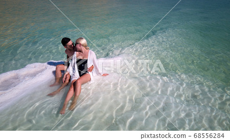 Aerial image of Beautiful models passionate couple kissing and embracing in the seawater. dead sea Israel Aerial image of Beautiful models passionate couple kissing and embracing in the seawater. dead sea Israel 68556284