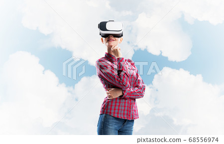 Girl in checked shirt wearing VR glasses experiencing another reality Girl in checked shirt wearing VR glasses experiencing another reality 68556974