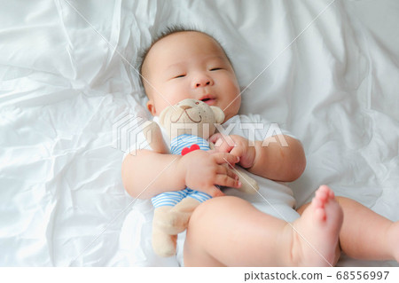 Portrait of little newborn baby boy laying with pacifier on mouth,cute child baby on white bed relax and to deliver Portrait of little newborn baby boy laying with pacifier on mouth,cute child baby on white bed relax and to deliver 68556997