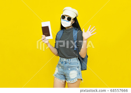 Traveler tourist young beautiful asian woman in hat and sunglasses with backpack,wearing medical face mask holding passport on yellow background.Summer holidays, vacation and travel concept Traveler tourist young beautiful asian woman in hat and sunglasses with backpack,wearing medical face mask holding passport on yellow background.Summer holidays, vacation and travel concept 68557666