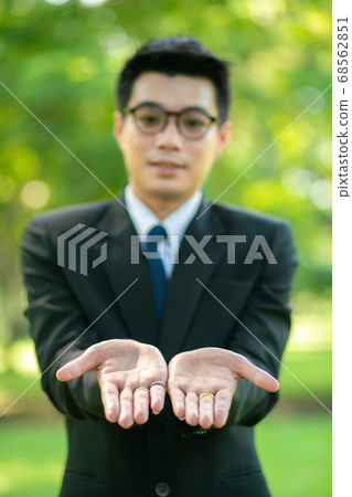 Handsome business man show blank hand in city park Handsome business man show blank hand in city park 68562851