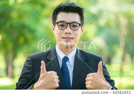 Handsome business man show blank hand in city park Handsome business man show blank hand in city park 68562853