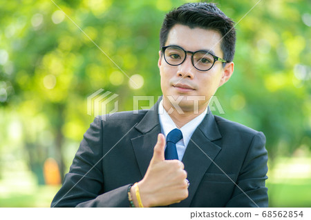 Handsome business man show blank hand in city park Handsome business man show blank hand in city park 68562854