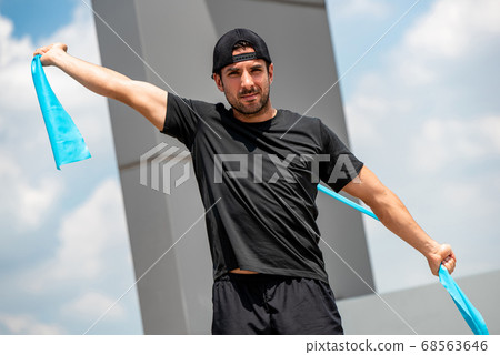 Handsome athletic man stretching with resistance band outdoors Handsome athletic man stretching with resistance band outdoors 68563646