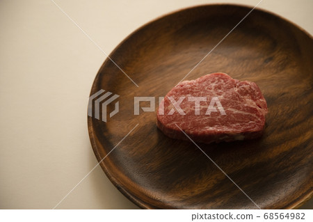 Raw thick beef fillet steak on acacia plate Raw thick beef fillet steak on acacia plate 68564982