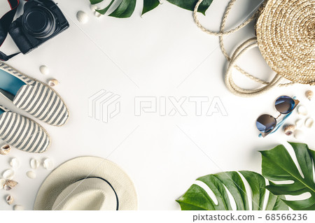 Straw hat, camera, bag, summer shoes, sunglasses, shells and tropical leaves over white background, top view. Straw hat, camera, bag, summer shoes, sunglasses, shells and tropical leaves over white background, top view. 68566236