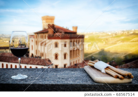 Chalice of wine with breadsticks and the castle of Barolo, Italy Chalice of wine with breadsticks and the castle of Barolo, Italy 68567514