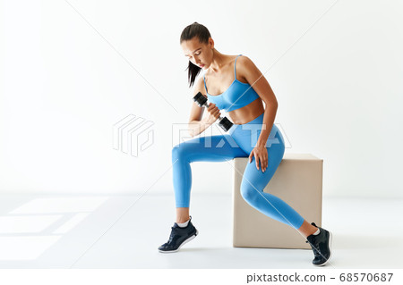 Sporty woman in sportswear doing exercise with dumbbells on white background with copy space 68570687