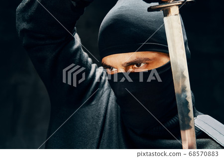 Fighting ninja posing with a sword over black background 68570883