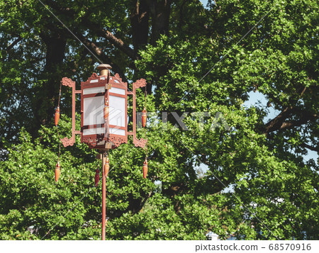 An old Chinese lantern on a green tree background An old Chinese lantern on a green tree background 68570916
