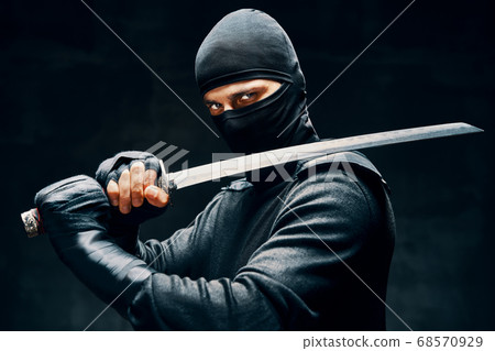 Fighting ninja posing with a sword over black background Fighting ninja posing with a sword over black background 68570929