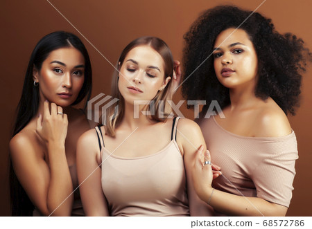 young pretty asian, caucasian, afro woman posing cheerful together on brown background, lifestyle diverse nationality people concept 68572786