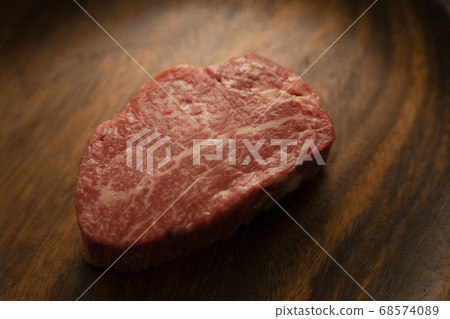 Raw thick beef fillet steak on acacia plate 68574089