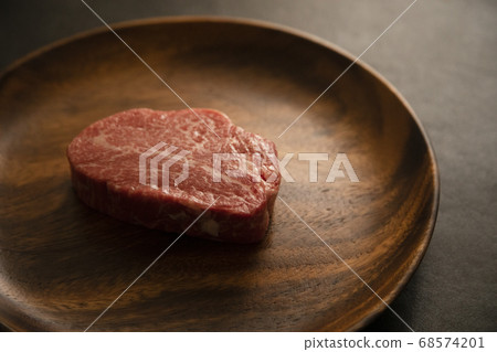 Raw thick beef fillet steak on acacia plate 68574201