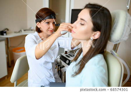 Female ent doctor and patient in office, ear exam 68574301