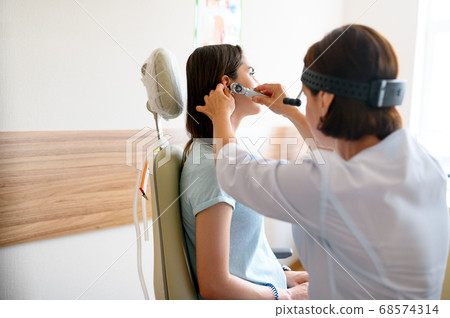 Female ent doctor and patient in office, ear exam 68574314
