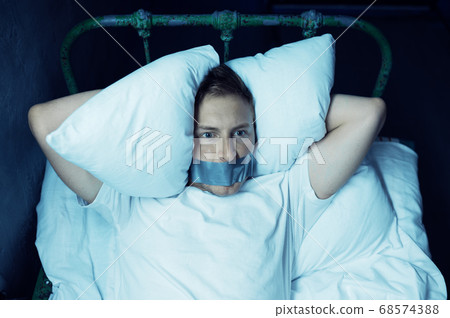 Psycho man with taped mouth lying in bed 68574388