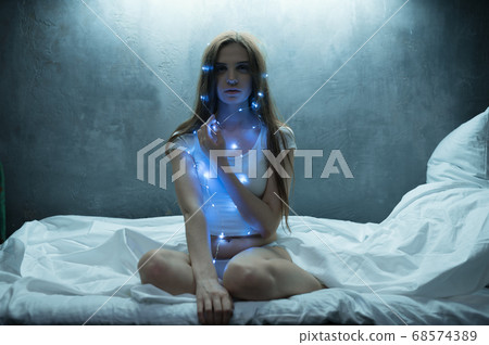 Mad woman in garlands sitting in bed, insomnia 68574389