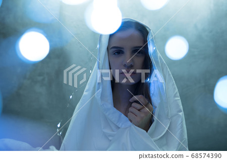 Mad woman in garlands sitting in bed, insomnia 68574390