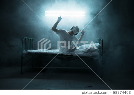 Blindfolded psycho man sitting in bed, hospital Blindfolded psycho man sitting in bed, hospital 68574408