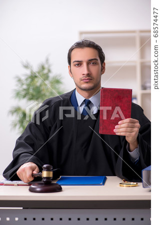 Young male judge working in courthouse 68574477