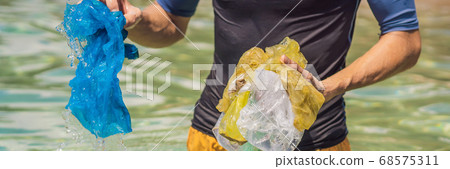 Man collects packages from the beautiful turquoise sea. Paradise beach pollution. Problem of spilled rubbish trash garbage on the beach sand caused by man-made pollution and environmental, campaign to Man collects packages from the beautiful turquoise sea. Paradise beach pollution. Problem of spilled rubbish trash garbage on the beach sand caused by man-made pollution and environmental, campaign to 68575311