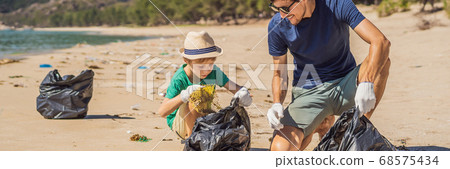 Dad and son in gloves cleaning up the beach pick up plastic bags that pollute sea. Natural education of children. Problem of spilled rubbish trash garbage on the beach sand caused by man-made Dad and son in gloves cleaning up the beach pick up plastic bags that pollute sea. Natural education of children. Problem of spilled rubbish trash garbage on the beach sand caused by man-made 68575434