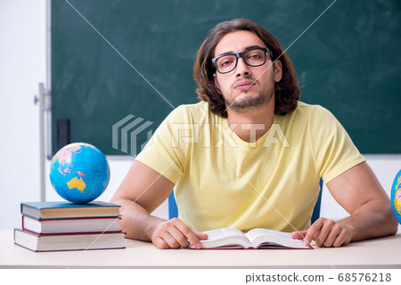 Young male geography teacher in front of blackboard 68576218