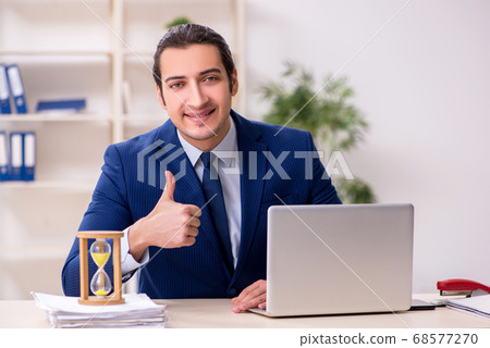 Young male employee in time management concept Young male employee in time management concept 68577270