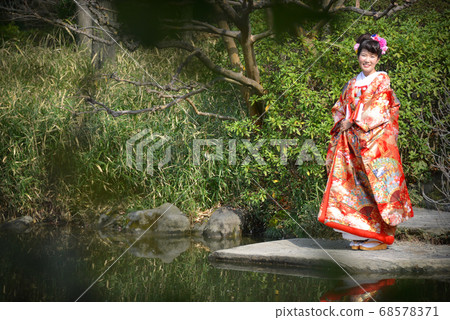 A woman wearing a color coat in a Japanese garden A woman wearing a color coat in a Japanese garden 68578371