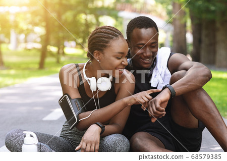 Black Couple Using Smartwatch Fitness Tracker After Outdoor Workout, Checking Burned Calories 68579385