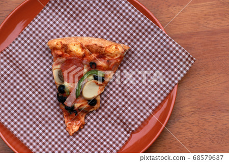 A piece of triangle Pizza  place on brown scotch paper  in the brown round plate 68579687