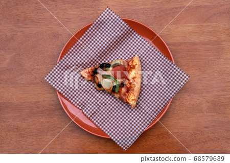 A piece of triangle Pizza place on brown scotch paper  in the brown round plate 68579689