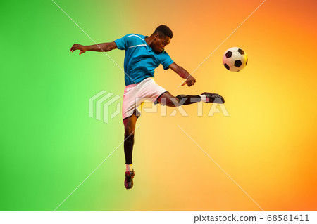 Male soccer, football player training in action isolated on gradient studio background in neon light Male soccer, football player training in action isolated on gradient studio background in neon light 68581411