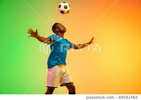 Male soccer, football player training in action isolated on gradient studio background in neon light Male soccer, football player training in action isolated on gradient studio background in neon light 68581468