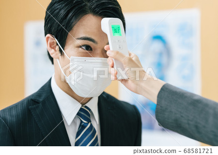 一個穿著西裝的男人的溫度測量現場 68581721