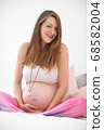 Pregnant woman sitting on her bed 68582004