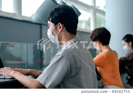 Masked business person working at a social distance at the office counter Masked business person working at a social distance at the office counter 68582753