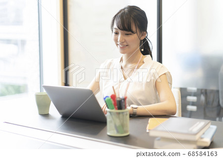 一個女人在辦公室的窗戶旁的座位上操作計算機 一個女人在辦公室的窗戶旁的座位上操作計算機 68584163