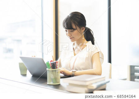 一個女人在辦公室的窗戶旁的座位上操作計算機 一個女人在辦公室的窗戶旁的座位上操作計算機 68584164