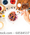 Top view showing hands eating porridge with honey nuts, blueberries on white wooden table selective focus, blurred background Good morning - healthy breakfast background 68584537