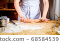 Female hands rolling out dough on kitchen table, close up 68584539