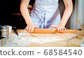 Female hands rolling out dough on kitchen table, close up 68584540