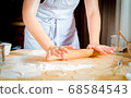 Female hands rolling out dough on kitchen table, close up 68584543