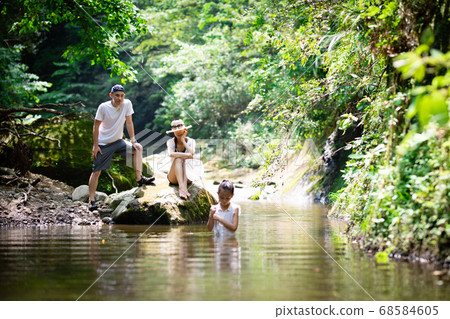 Father, mother and daughter playing in the mountain stream 68584605