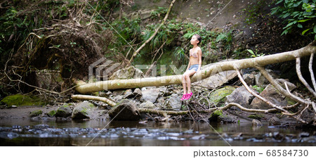 Girl sitting on a fallen tree 68584730