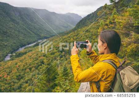 Hike woman hiker taking picture with phone of river view from top of trail hiking in Parc National de la Jacques Cartier, Quebec, Canada autumn travel camping lifestyle Hike woman hiker taking picture with phone of river view from top of trail hiking in Parc National de la Jacques Cartier, Quebec, Canada autumn travel camping lifestyle 68585255