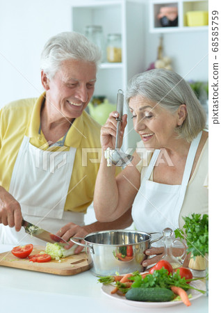 Portrait of senior couple cooking together at kitchen Portrait of senior couple cooking together at kitchen 68585759